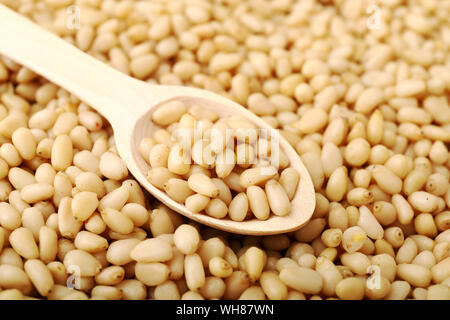 Pine nuts on a wooden spoon on background texture of shelled pine nuts Stock Photo