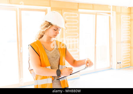 Young woman checking the construction of a new wooden house Stock Photo