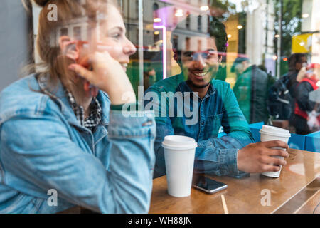 Portrait of smiling young man in a coffee shop listening to young woman Stock Photo