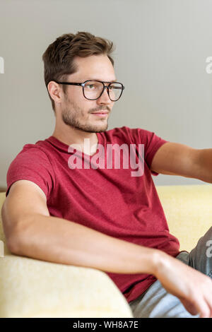 Pensive man sitting on a couch Stock Photo