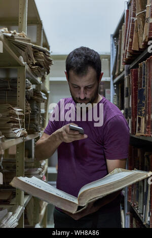 Man taking pictures of an old book at National library, Maputo, Mocambique Stock Photo