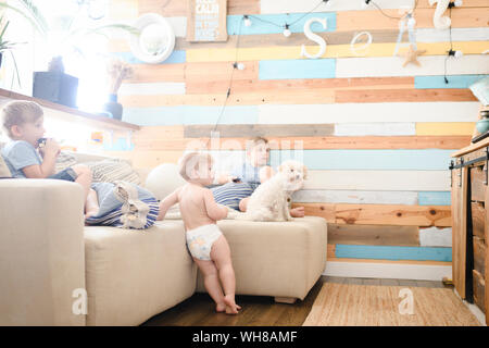 Three brothers and little dog relaxing on the couch watching TV Stock Photo