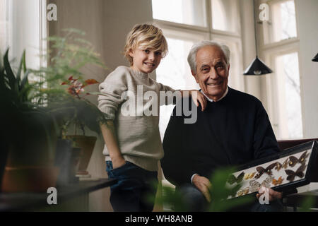 Grandfather showing butterfly collection to grandson at home Stock Photo
