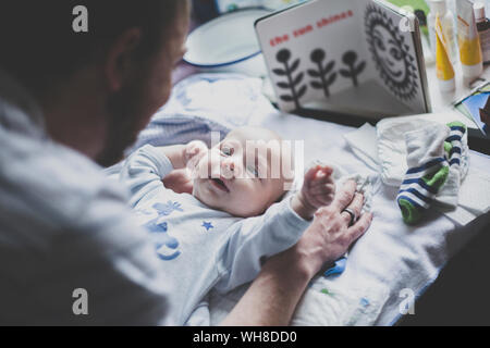 Father playing with his baby son on changing table Stock Photo