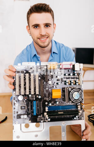 Portrait of smiling technician holding the mainboard of a computer Stock Photo