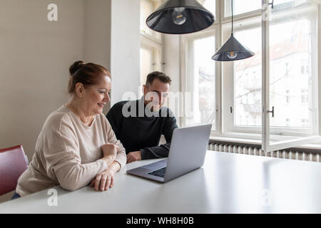 Smiling senior woman and man looking at laptop on table Stock Photo