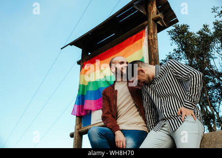 Happy gay couple with gay pride flag on a trip Stock Photo