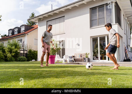 Father and son playing football in garden Stock Photo