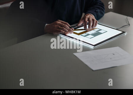 Close-up of senior man using tablet with architectural plan Stock Photo