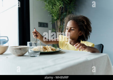 Girl eating pasta at dining table Stock Photo