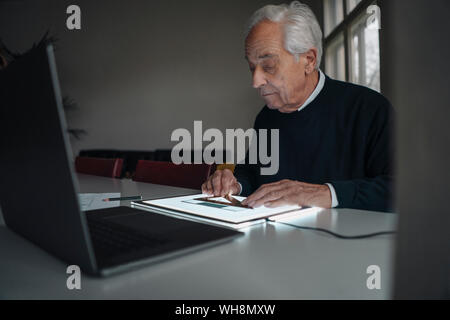 Senior man using tablet with architectural plan Stock Photo