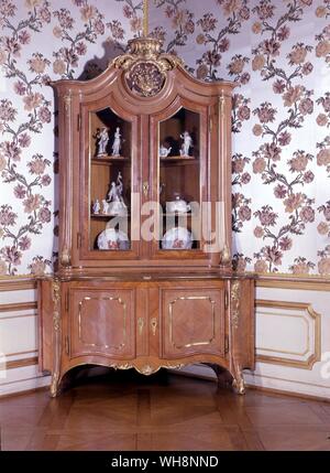 A corner cupboard of cedar wood with bronze fittings by J. A. Nahl, Berlin, about 1745, after a design by Knobelsdorff. The Berlin porcelain includes a shepherd and shepherdess by F. E. Meyer. a Gotzkowski teapot. a cherub from the service of the Potsdam palace. Fama, also by F. E. Meyer. two figures by C. W. Meyer and two plates from the Charlottenburg service. Stock Photo