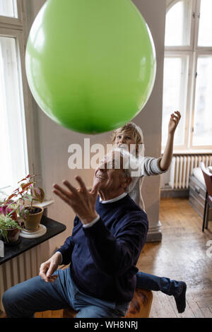 Happy grandfather and grandson playing with balloon at home Stock Photo