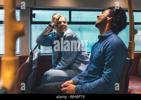 Young couple travelling by bus on rainy day having fun, London, UK Stock Photo