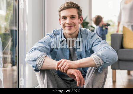 Confident man sitting on floor of his home, smiling Stock Photo