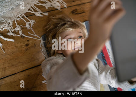Top view of boy lying on carpet using tablet Stock Photo