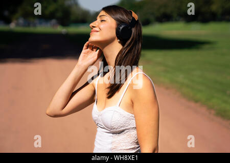 Portrait of young woman with headphones in a park in summer Stock Photo