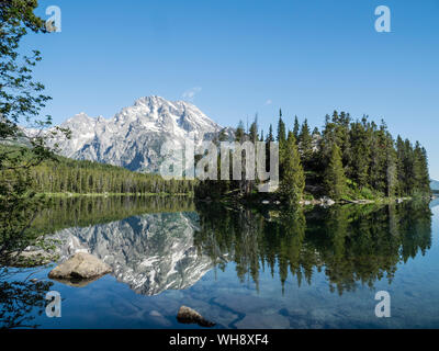 Snow-capped mountains reflected in the calm waters of Leigh Lake, Grand Teton National Park, Wyoming, United States of America, North America Stock Photo