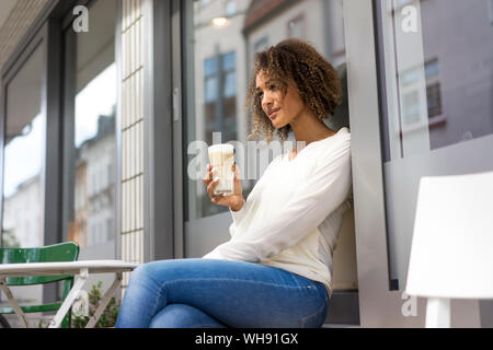 Young woman relaxing at pavement cafe with Latte Macchiato Stock Photo
