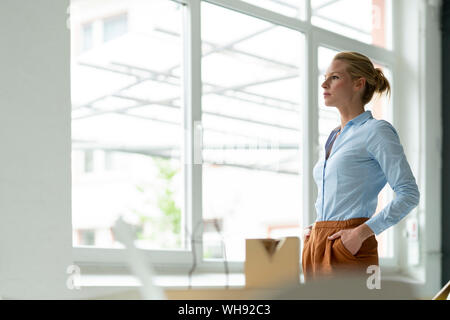 Serious young woman in office with architectural model on desk Stock Photo