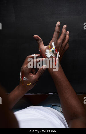 Dirty hands of artist with colorful paints against black background. London, UK. Stock Photo