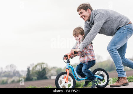 Father teaching his son how to ride a bicycle, outdoors Stock Photo