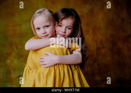Portrait of smiling girl hugging her little sister Stock Photo