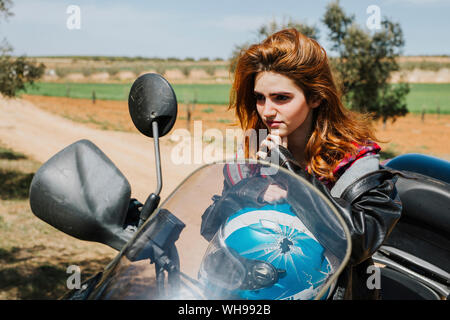 Portrait of redheaded woman on motorbike Stock Photo