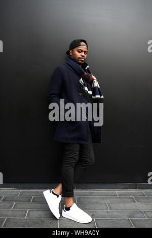 Portrait of fashionable man standing in front of dark background Stock Photo