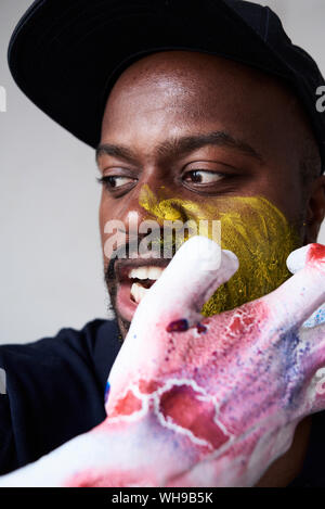 Angry artist with hand covered in paint looking at camera Stock Photo