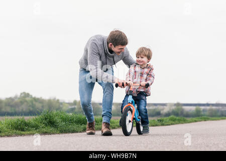 Father teaching his son how to ride a bicycle, outdoors Stock Photo