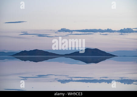 Pastel-coloured beauty of salt flats reflecting the clouds and mountains after rainfall just after sunset, Uyuni, Bolivia, South America Stock Photo