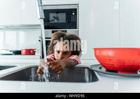 Girl washing her hands at kitchen sink Stock Photo