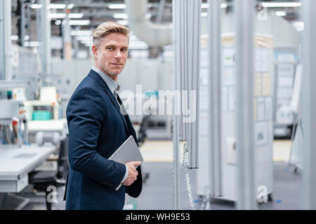 Confident businessman with tablet in a modern factory Stock Photo