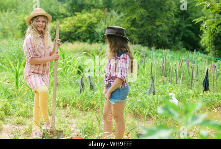 Agriculture concept. Sisters together helping at farm. Girls planting plants. Rustic children working in garden. Planting and watering. Planting vegetables. Growing vegetables. Hope for nice harvest. Stock Photo