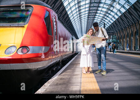 Young couple standing on platform looking at map, London, UK Stock Photo