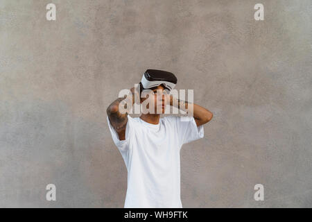 Tattooed young man with Virtual Reality Glasses looking up Stock Photo