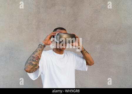 Tattooed young man using Virtual Reality Glasses looking up Stock Photo