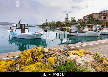 Colourful fishing nets on quay, boats, man mending nets, waterfront, Nafplio (Nafplion), Argolic Gulf, Peloponnese, Greece, Europe Stock Photo