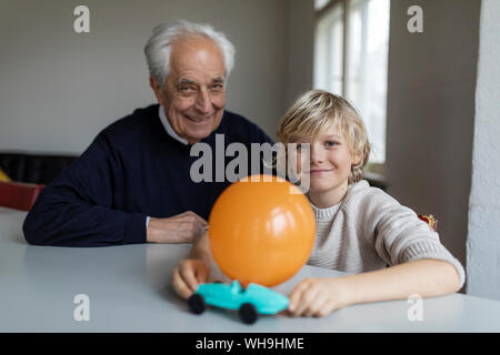 Happy grandfather and grandson playing with toy car and balloon at home Stock Photo