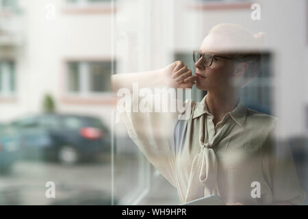Pensive young businesswoman looking out of window Stock Photo