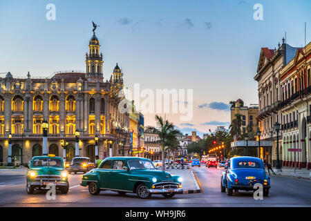 Vintage American cars turning and The Gran Teatro de La Habana at dusk, UNESCO, Havana, Cuba, West Indies, Caribbean, Central America Stock Photo