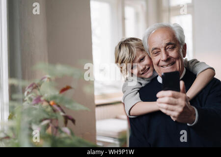 Happy grandfather and grandson using cell phone at home Stock Photo