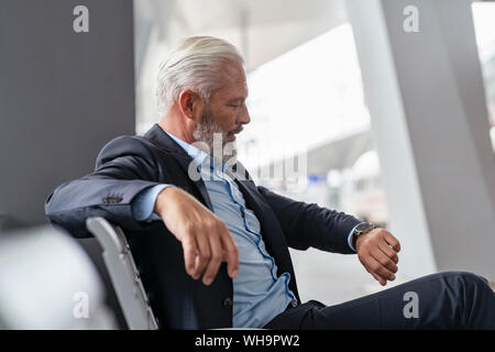 Mature businessman sitting in waiting area checking the time Stock Photo