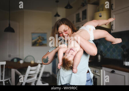 Portrait of mother playing with her little son in the kitchen Stock Photo