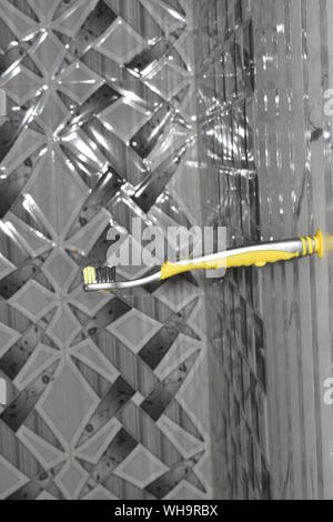 KID'S TOOTH BRUSH WHICH IS PLACED HORIZONTALLY ON THE VERTICAL WALL HAVING TILES Stock Photo