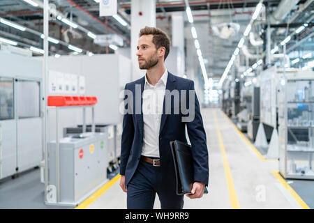 Businessman walking in a modern factory