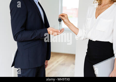 Close-up of real estate agent handing over key to client in new home Stock Photo