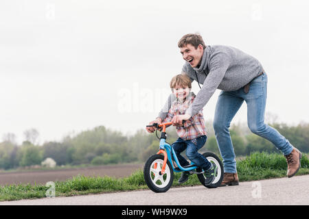 Father teaching his son how to ride a bicycle, outdoors Stock Photo
