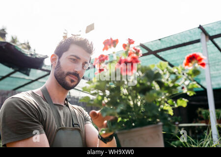 Worker in a garden center caring for a flower Stock Photo